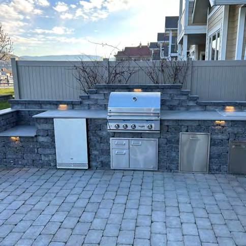 Built in outdoor kitchen with stone counter and paver patio
