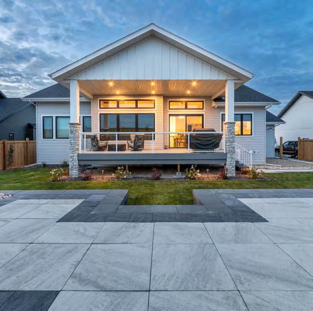 Covered outdoor living area lit at dusk above a paver terrace