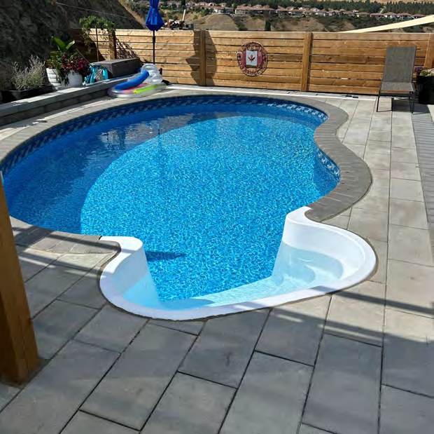 Freeform pool set into a large paver deck