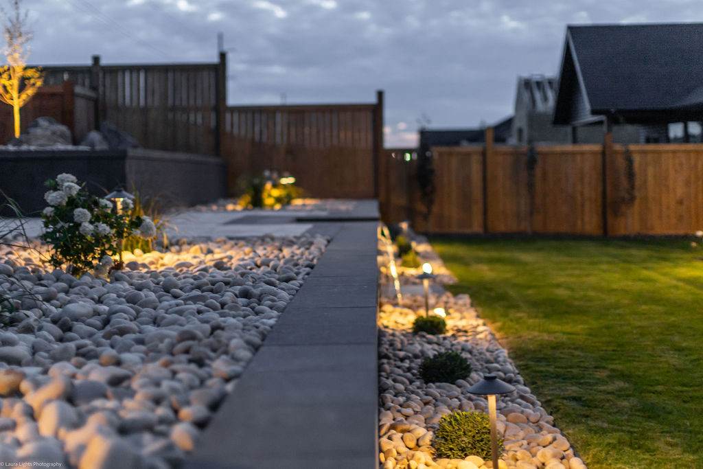 Paver path edged with river rock and low landscape lighting running along a lawn